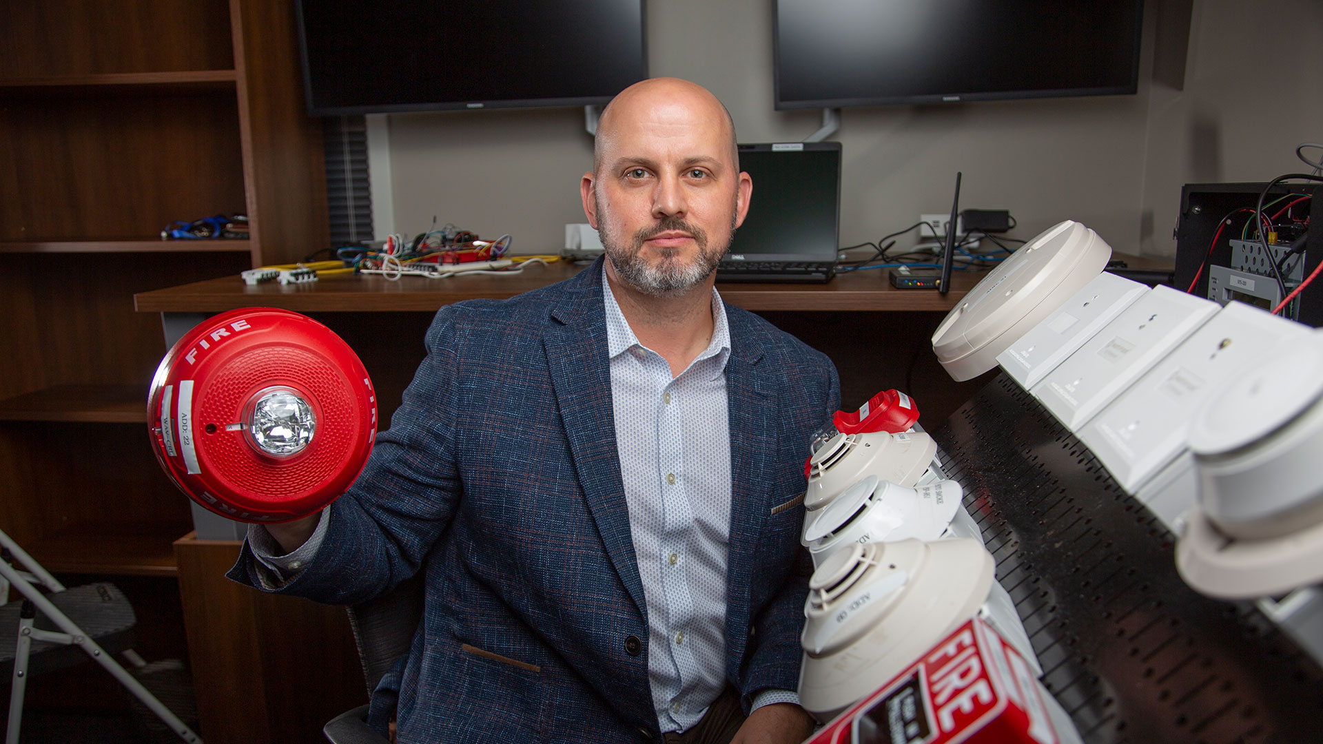 Researcher holding up fire alarm device.