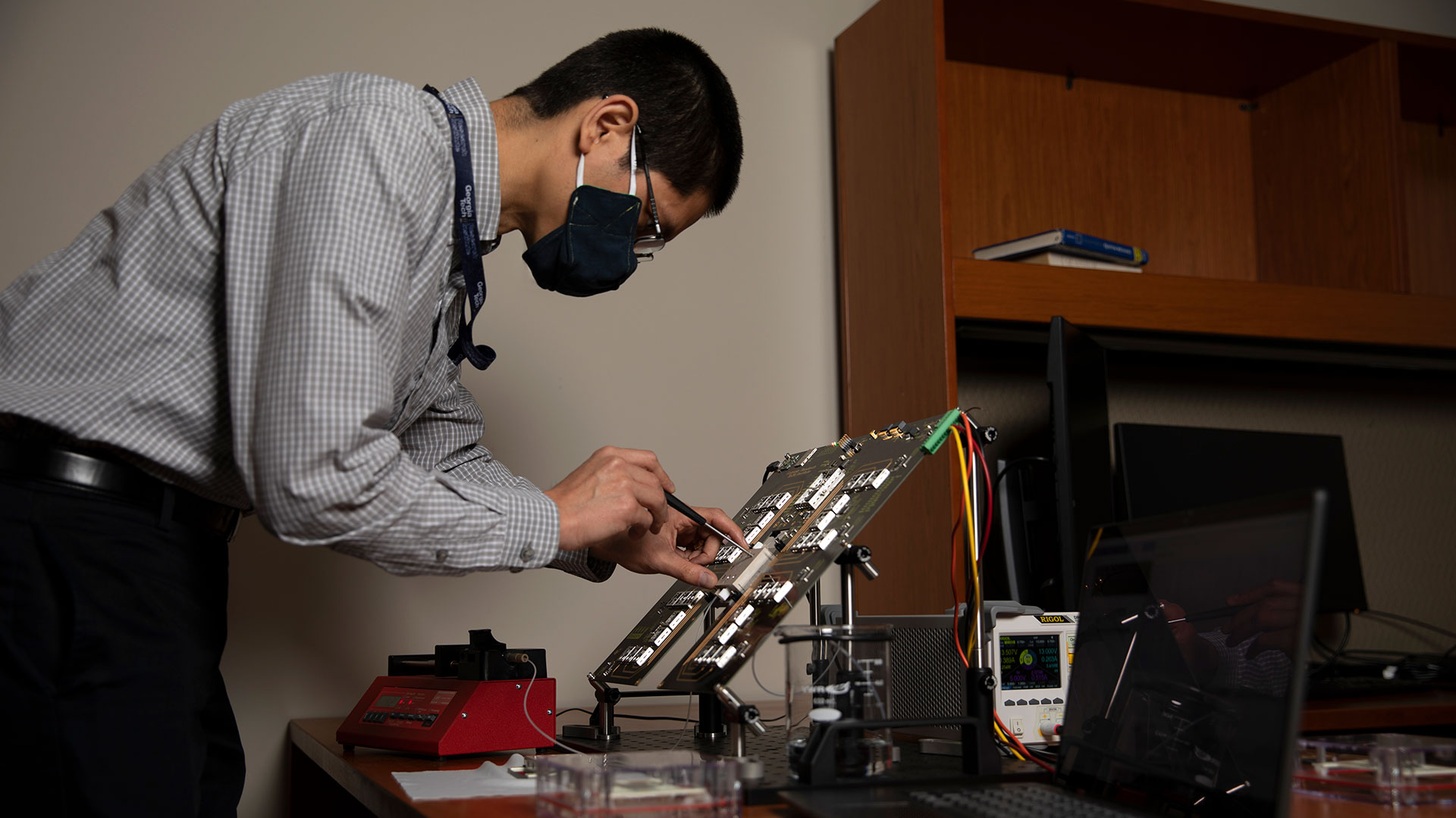 Research standing behind desk makes adjustments to device.