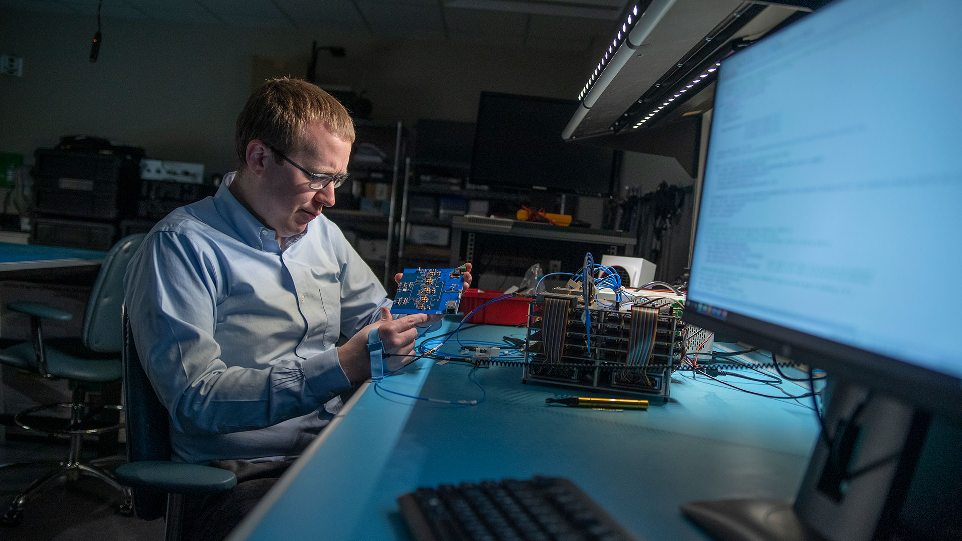 Researcher in lab sitting in front of large computer monitors.