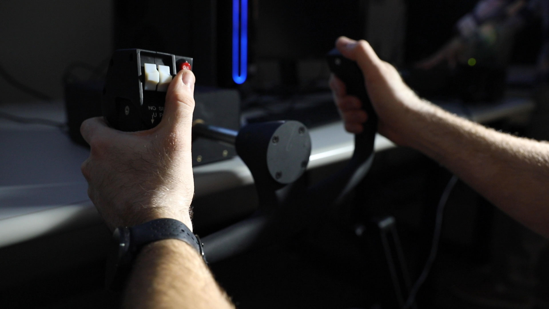 Hands of researcher on aircraft controls in lab setting.