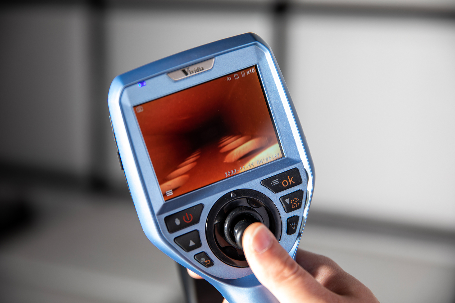 Researcher holds small device with screen display and control buttons.