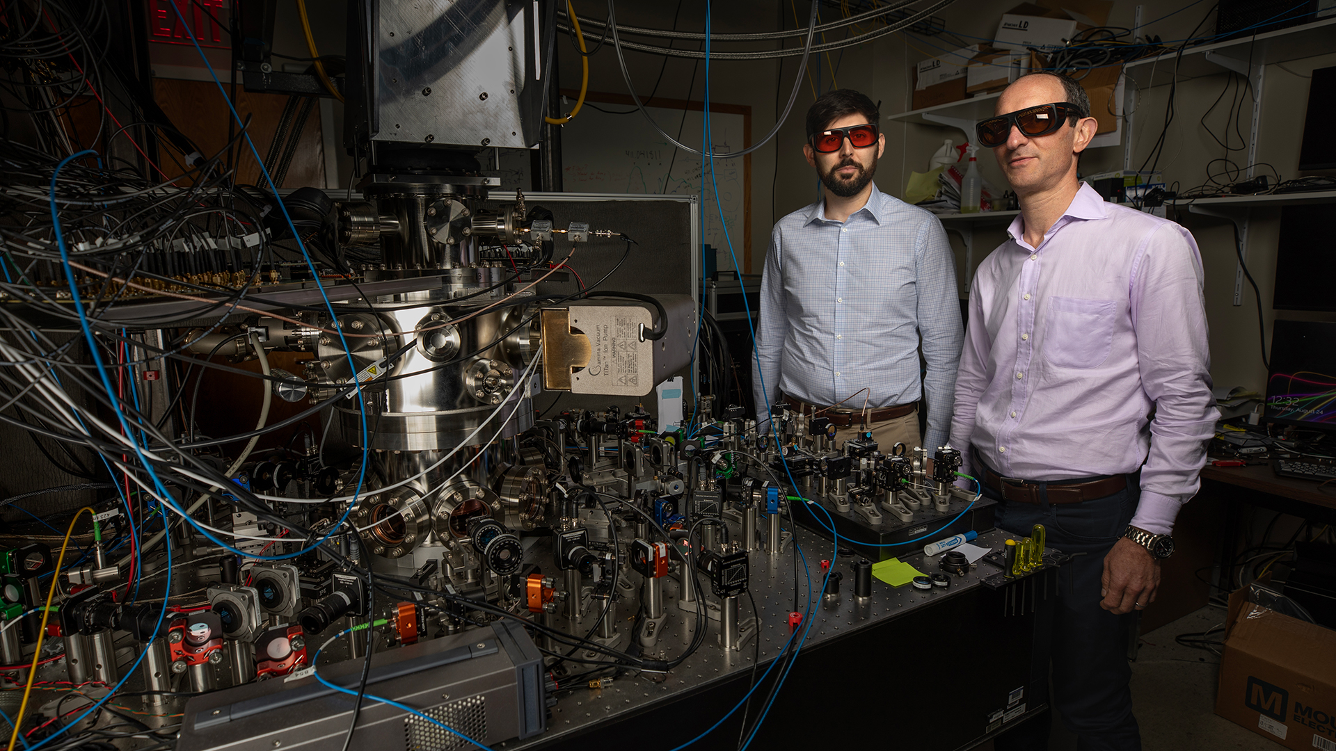 Researchers Spencer Fallek (left) and Kenton Brown shown with equipment used to develop a new technique for cooling ions in quantum devices. (Credit: Sean McNeil, GTRI)