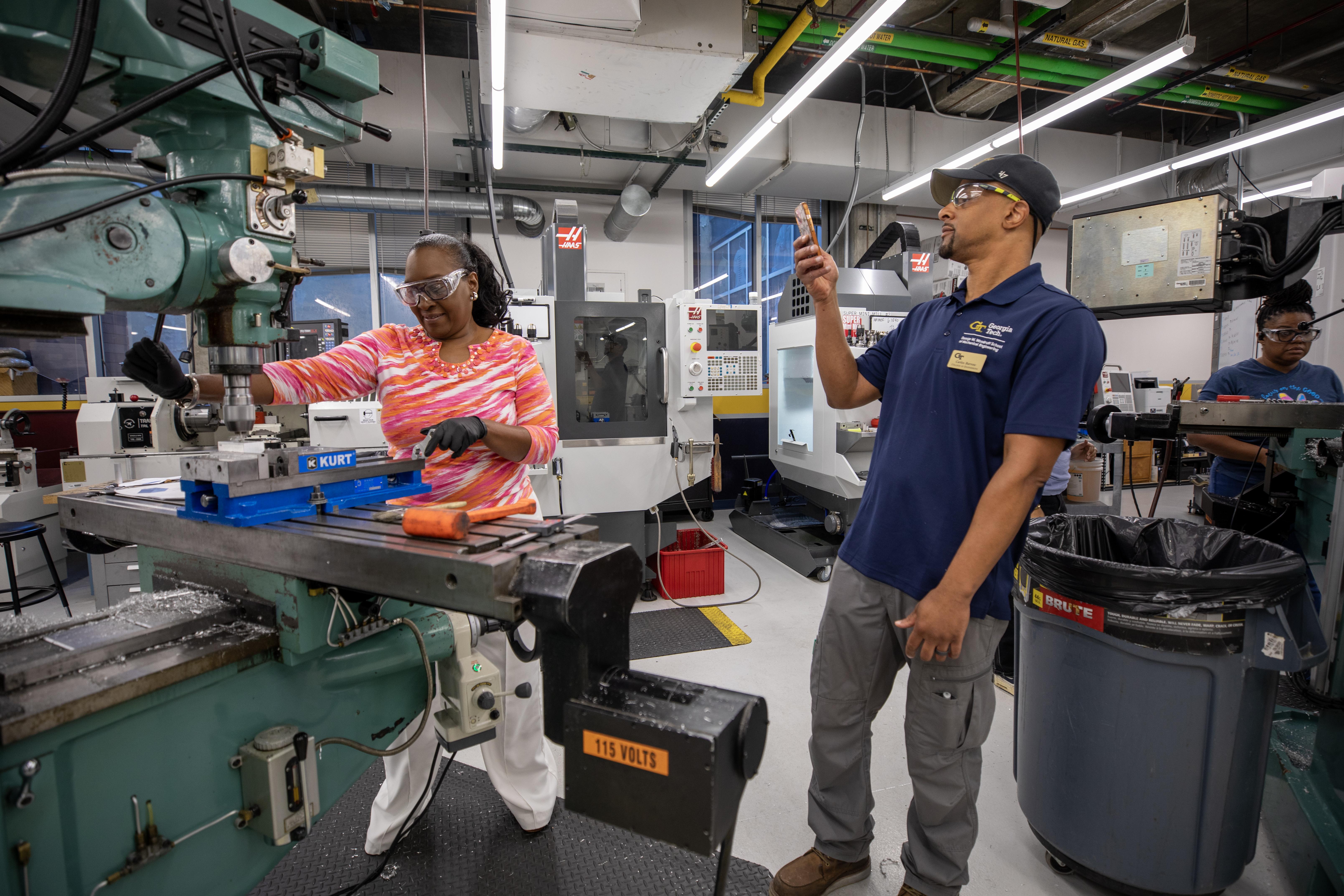 A participant at a Georgia Tech manufacturing workshop cuts metal on industrial equipment.