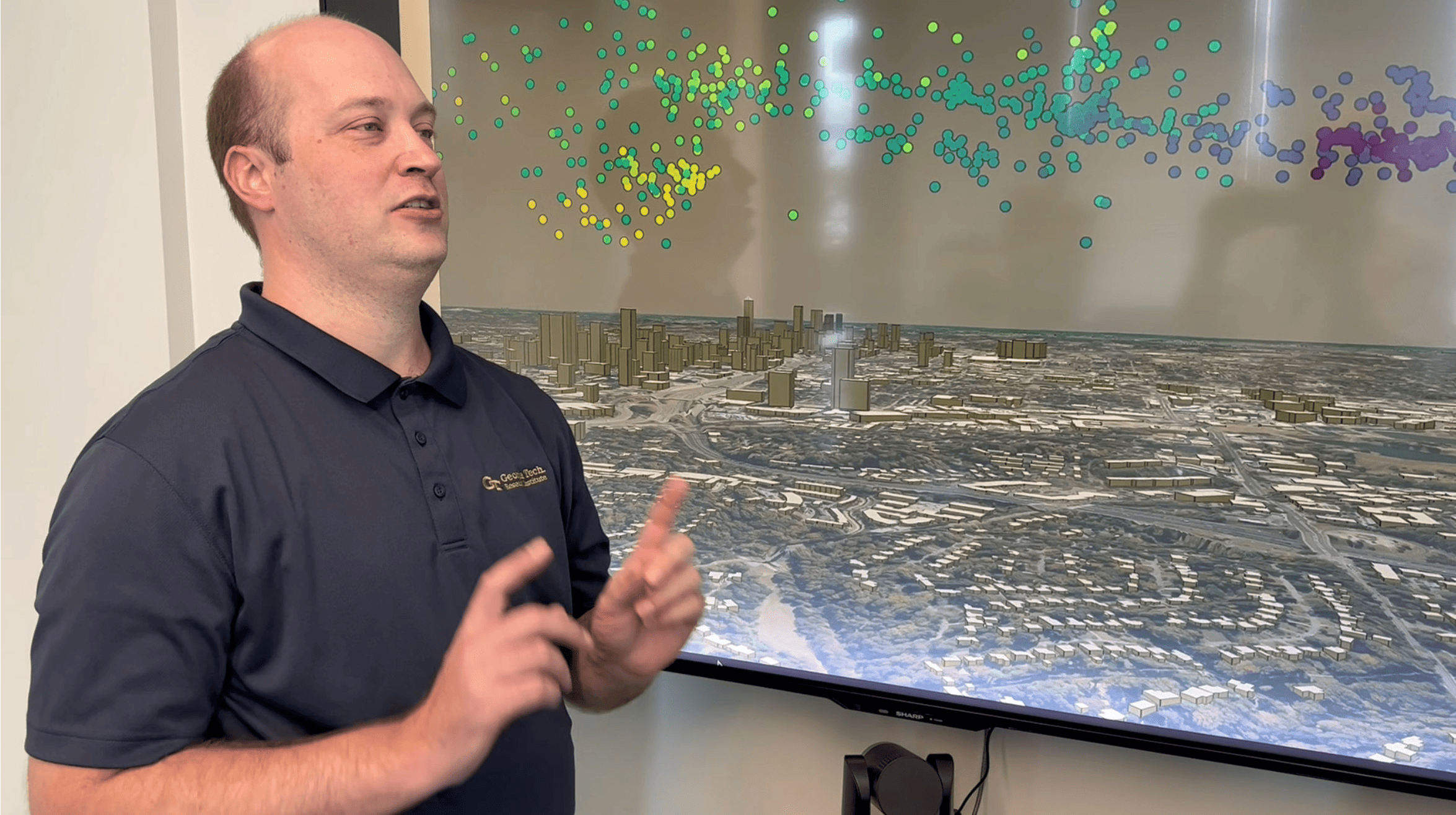 Researcher Michael Peterson with screen showing lightning “sources” (colored dots), which are the parts that make up a flash. Here the sources are shown in three dimensions above Atlanta.