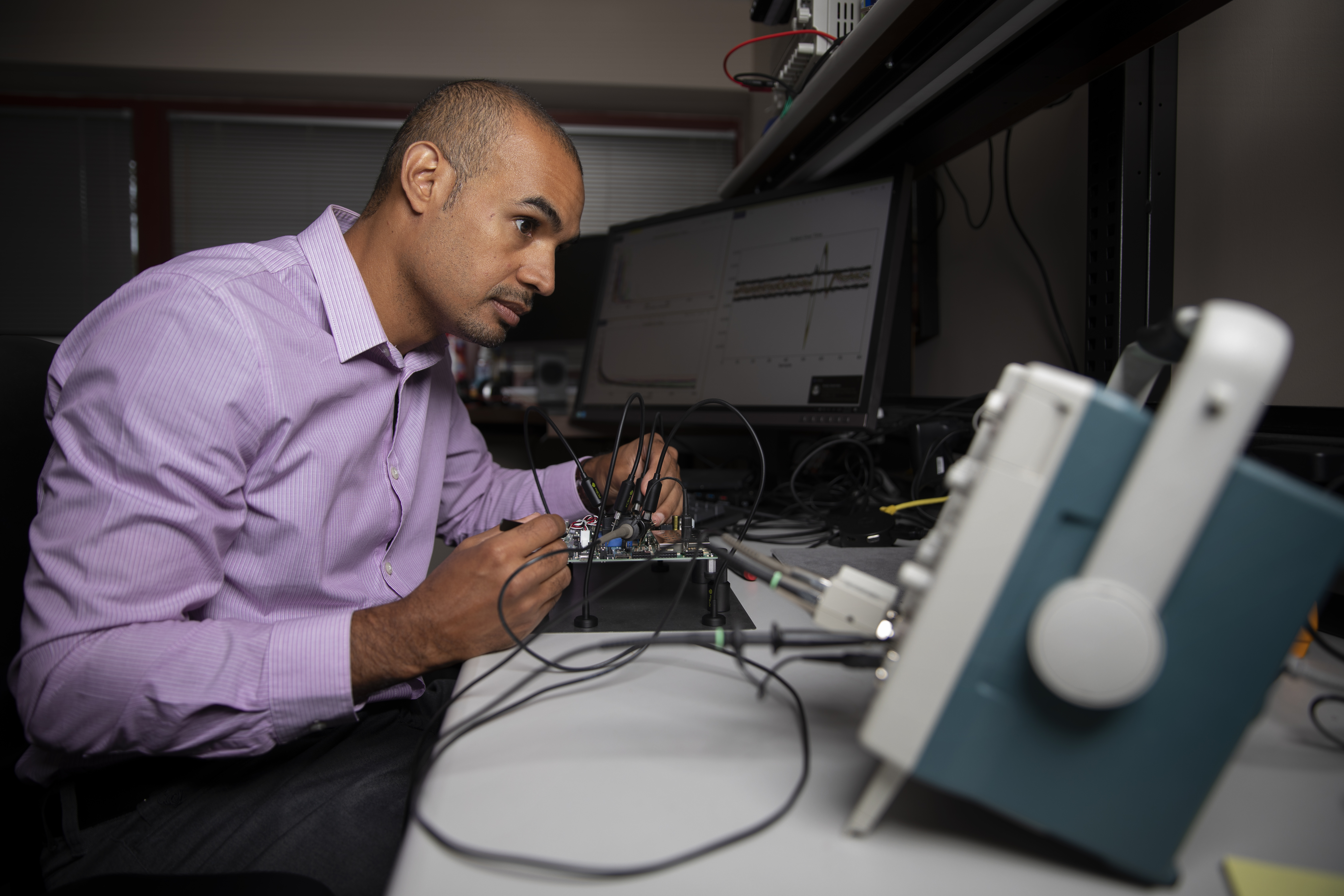 Mike Ruiz is shown using an oscilloscope, a type of electronic test instrument that graphically displays varying signal voltages, (Photo credit: Sean McNeil)