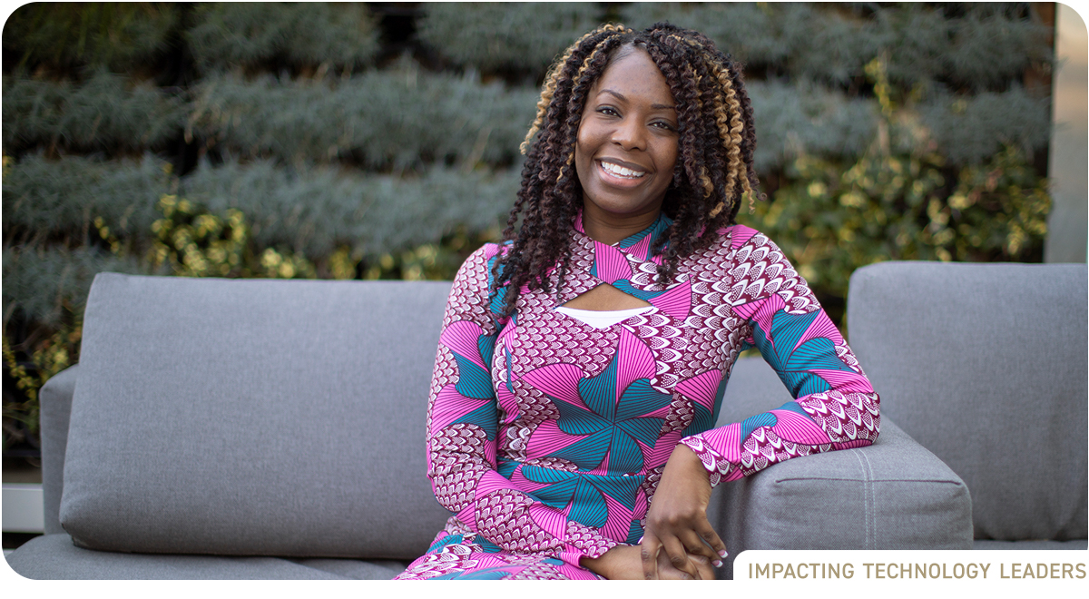 photo: young Black woman in brightly colored dress sits on sofa in office