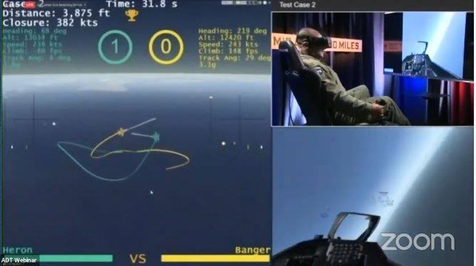 A screen capture from the livestreamed AlphaDogfight event from Zoom. On the left side is an image of the virtual reality where the dogfight took place, and on the right is the human pilot, who is controlling his virtual jet. 