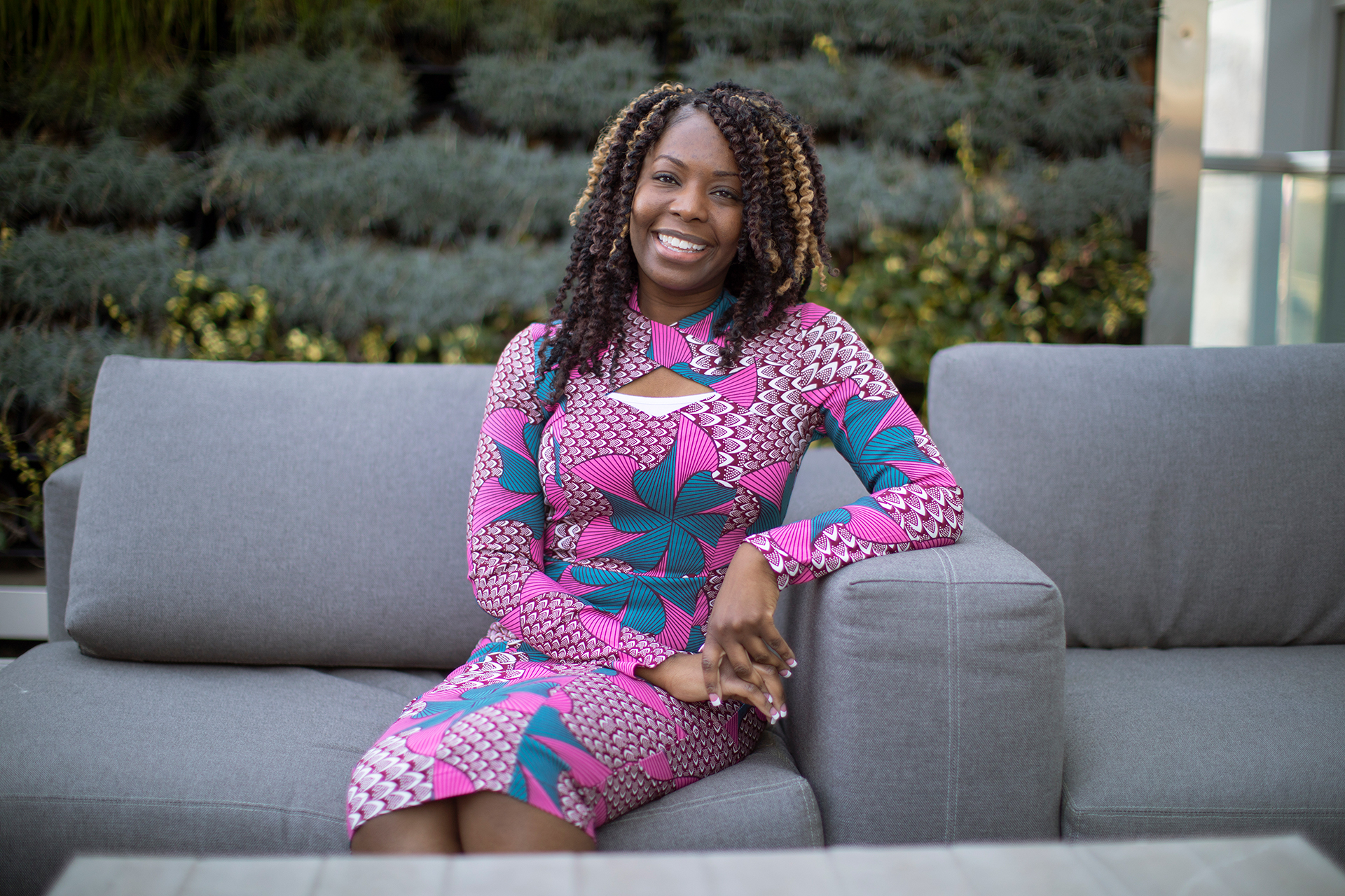 photo: young Black woman in brightly colored dress sitting on couch at GTRI offices