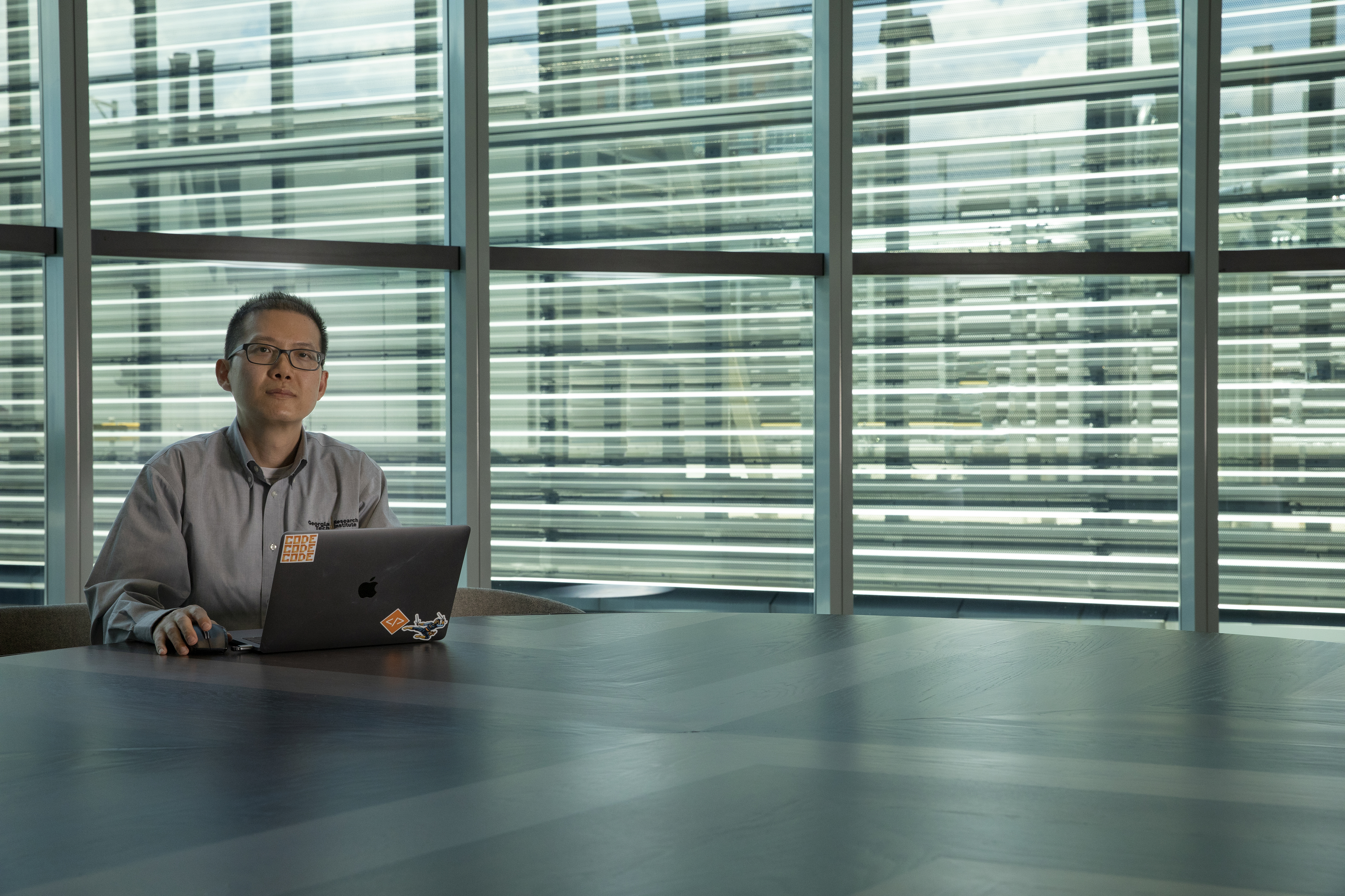 David Tran sit at his computer in front of a wall of windows. (Credit: Sean McNeil)