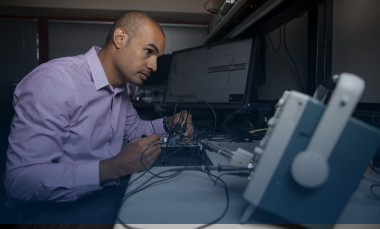 Mike Ruiz is shown using an oscilloscope, a type of electronic test instrument that graphically displays varying signal voltages, (Photo credit: Sean McNeil)