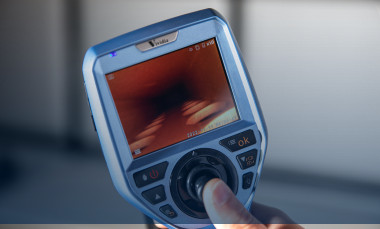 Researcher's hand holds measuring device that contains a display screen and control buttons.