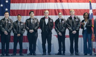 nine people standing in front of American flag accepting an award