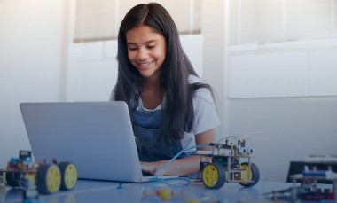 Female student sitting at a computer building and programming robot vehicle