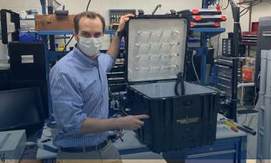 GTRI researcher Robert Harris shows the prototype portable UV disinfection chamber, which was designed to hold at least one face shield along with face masks. (Credit: John Stone)  