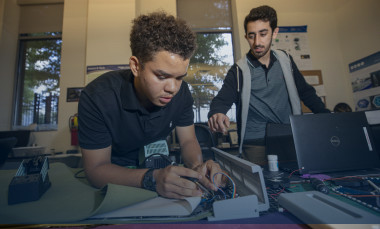 A high school student completing a STEM project with instructor looking over his shoulder. 