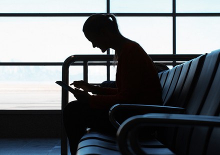 Photo: Woman in airport looking at iOS device