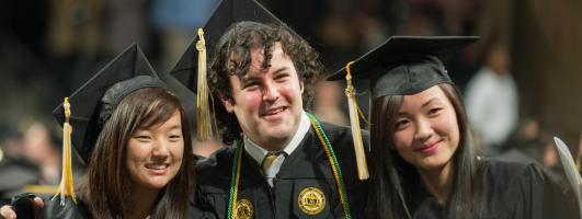 Three students in cap and gown on graduation