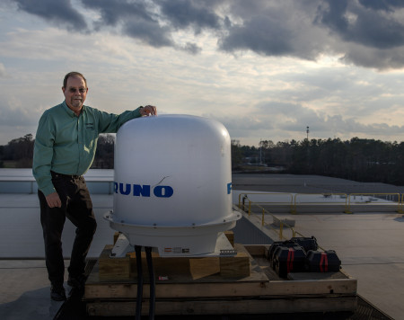 John Trostel standing next to new radar unit on the roof of GTRI's Cobb County facility