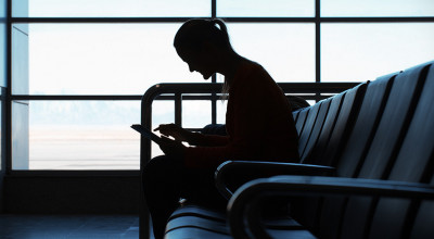 Photo: Woman in airport looking at iOS device