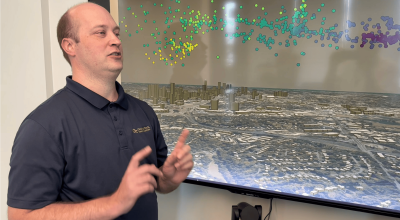 Researcher Michael Peterson with screen showing lightning “sources” (colored dots), which are the parts that make up a flash. Here the sources are shown in three dimensions above Atlanta.